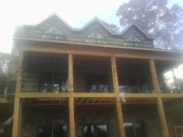 Dormers and porch framing on a large log home under construction — Roof Coating work by our crew in Athol