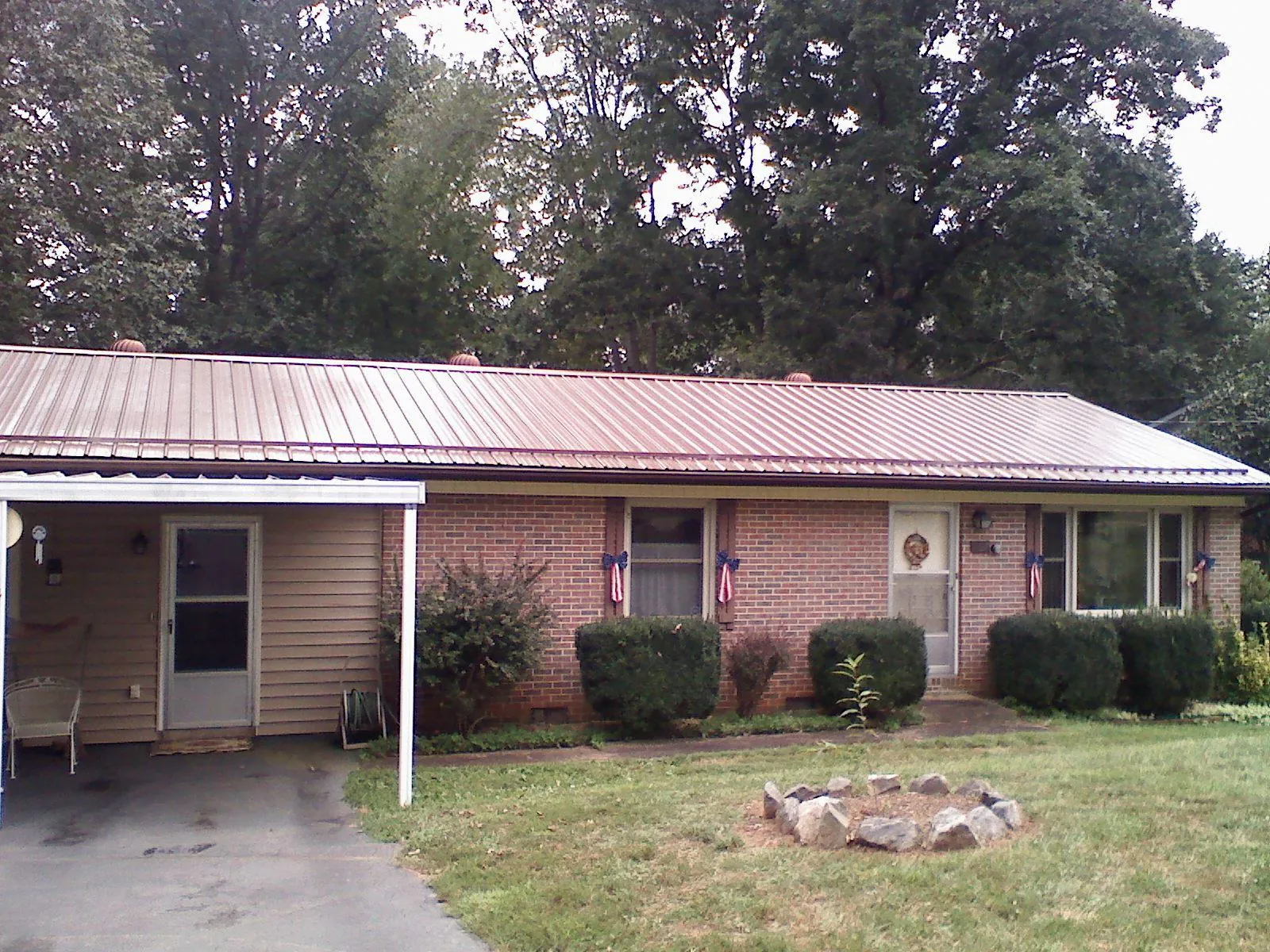 Bronze metal roof and carport on a brick ranch home — Roof Repair work by our crew in Athol